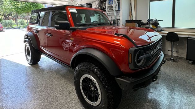 A red ford bronco is parked in a garage.