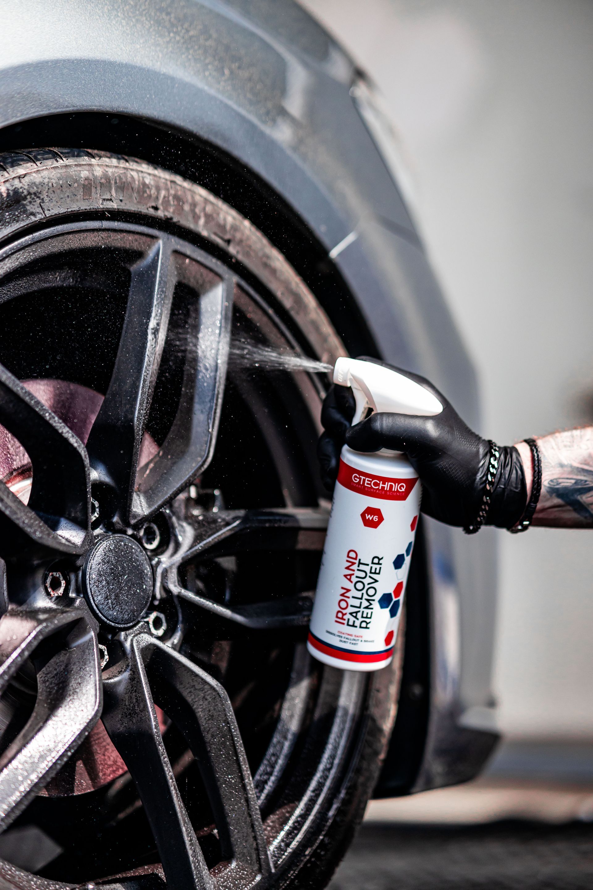 A person is cleaning a car wheel with a spray bottle.