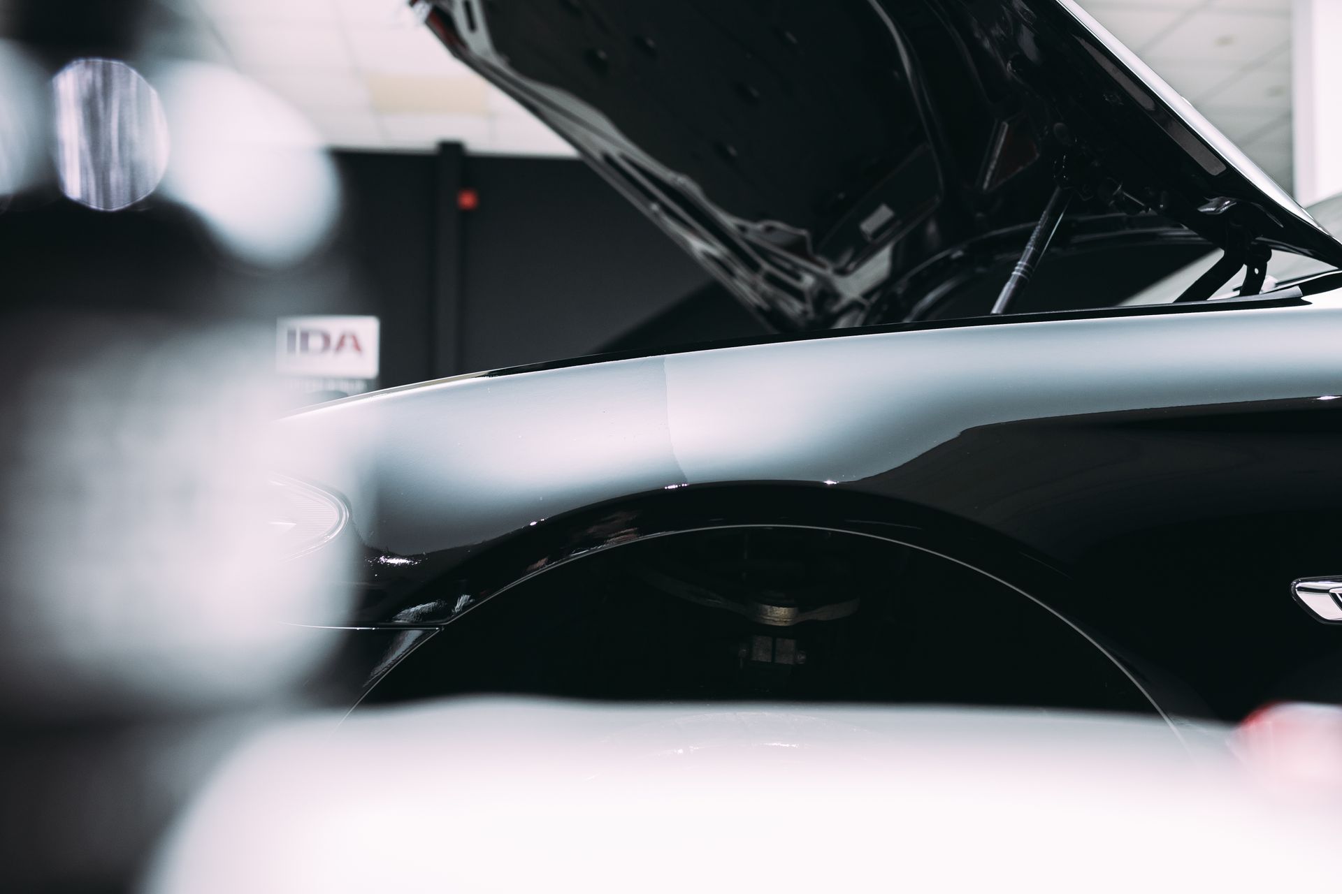 The hood of a car is open in a garage.
