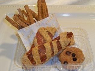 A plastic container filled with french fries , a hot dog , and a cookie.