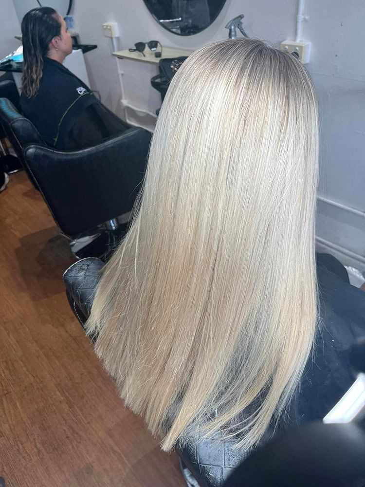 A Woman With Blonde Hair is Sitting in a Chair at a Hair Salon — Hairenvy in Ettalong Beach, NSW