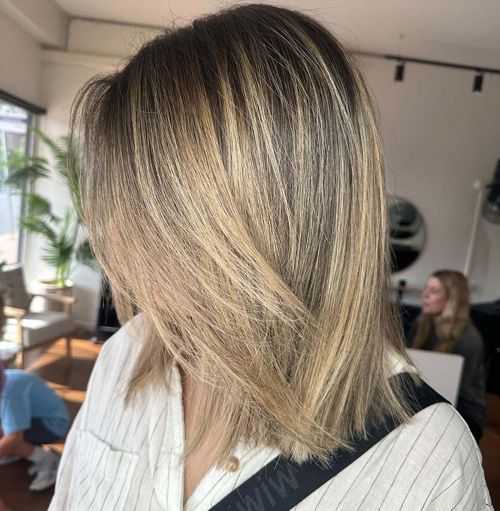 A Woman With Blonde Hair is Wearing a White Striped Shirt — Hairenvy in Ettalong Beach, NSW
