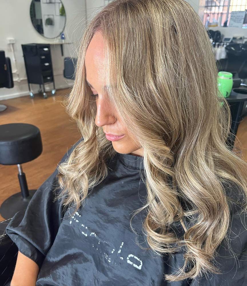 A Woman With Long Blonde Hair is Sitting in a Chair in a Salon — Hairenvy in Ettalong Beach, NSW