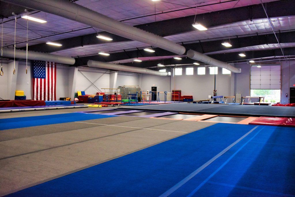 A large gym with a blue mat and an american flag on the wall.