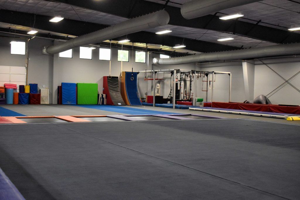 A large empty gym with a trampoline in the middle of it.
