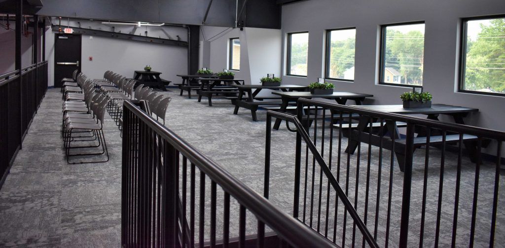 A long hallway with tables and chairs and a railing