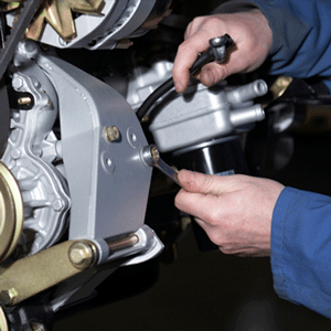 Manos utilizando una llave inglesa para ajustar una pieza mecánica plateada en una máquina.