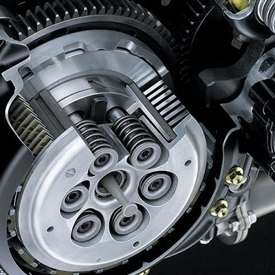Primer plano de un conjunto de embrague de motocicleta con engranajes y resortes metálicos dentro del motor.