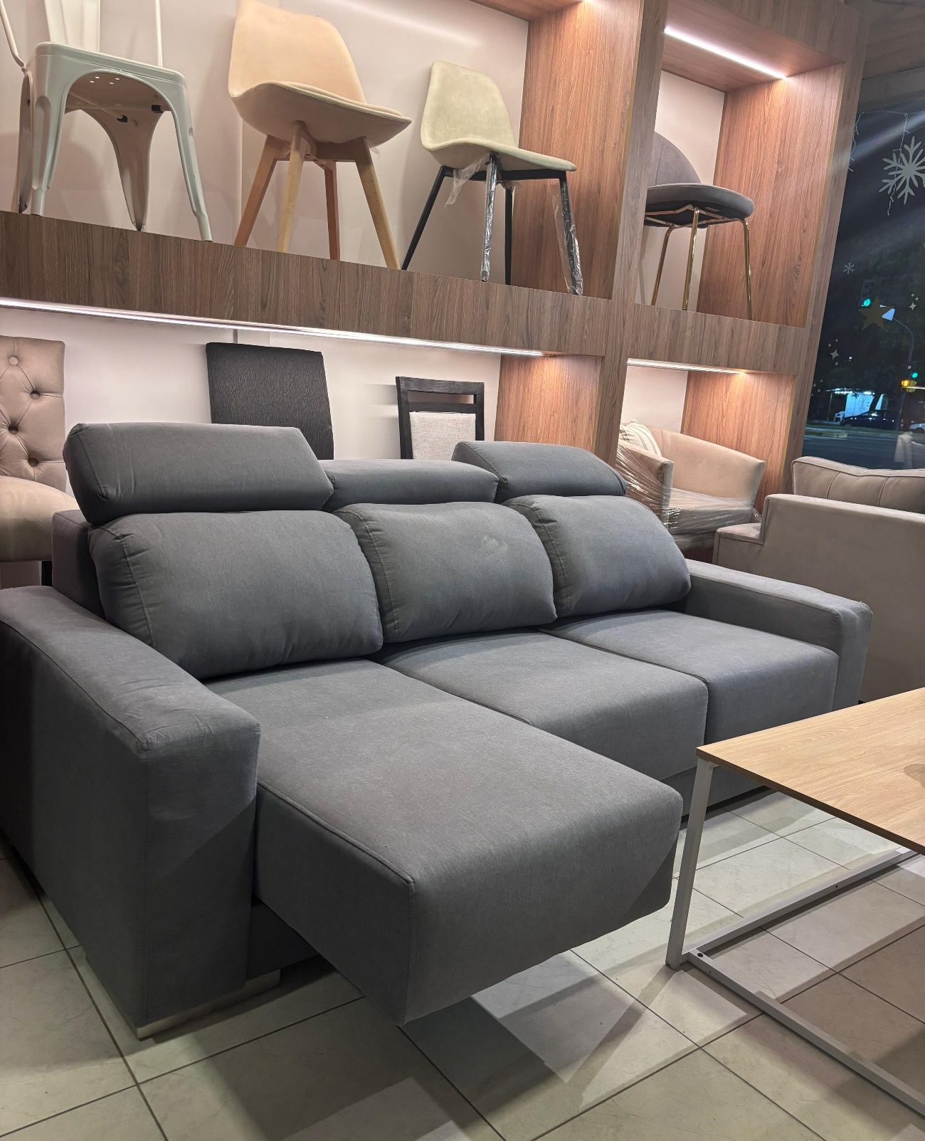 Sofá seccional gris con reposacabezas ajustables en una tienda de muebles.