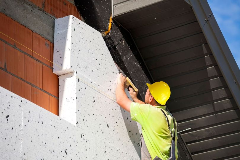 Operaio edile che installa l'isolamento sulla facciata esterna di un edificio.