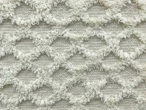 Light gray fabric with a raised diamond pattern edged in fluffy white fringe.