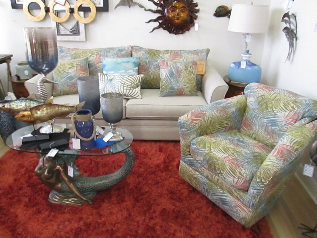 Living room display with a couch, armchair, mermaid coffee table, and red rug.