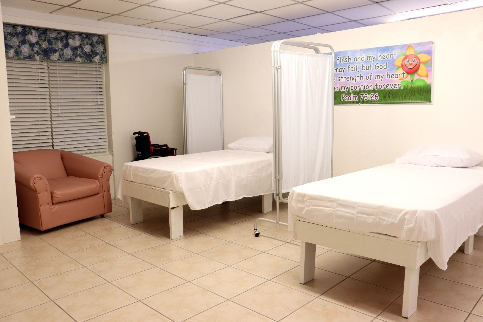 A hospital room with two beds and a chair