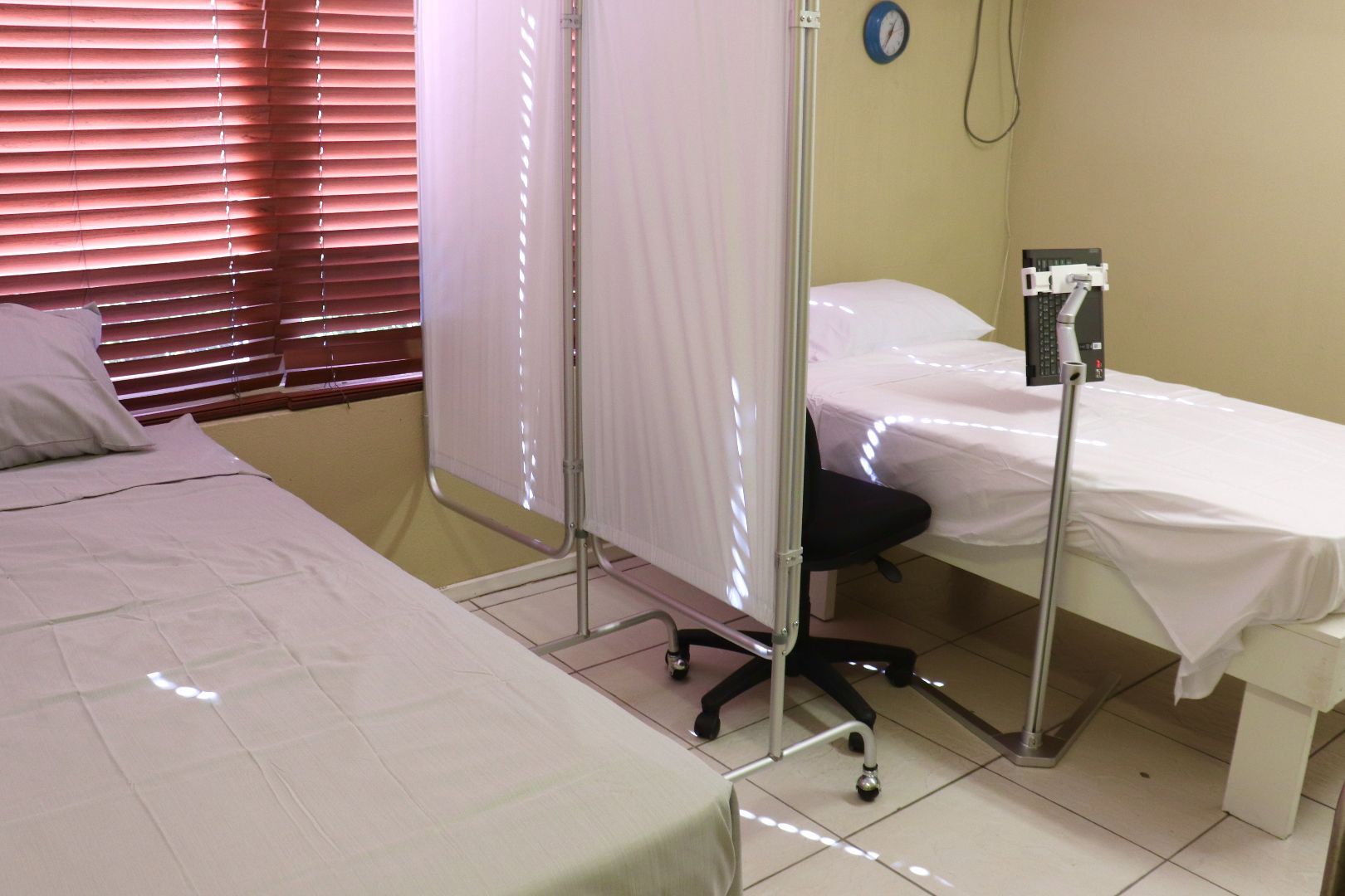 A hospital room with two beds and a clock on the wall