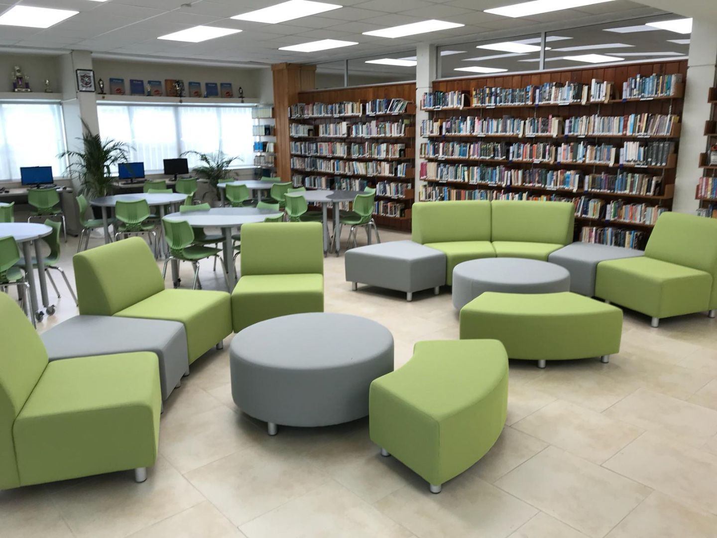 A library with green and grey furniture and tables