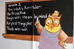 A cartoon owl is standing in front of a blackboard with the words grade 2 this week 's reminder written on it.
