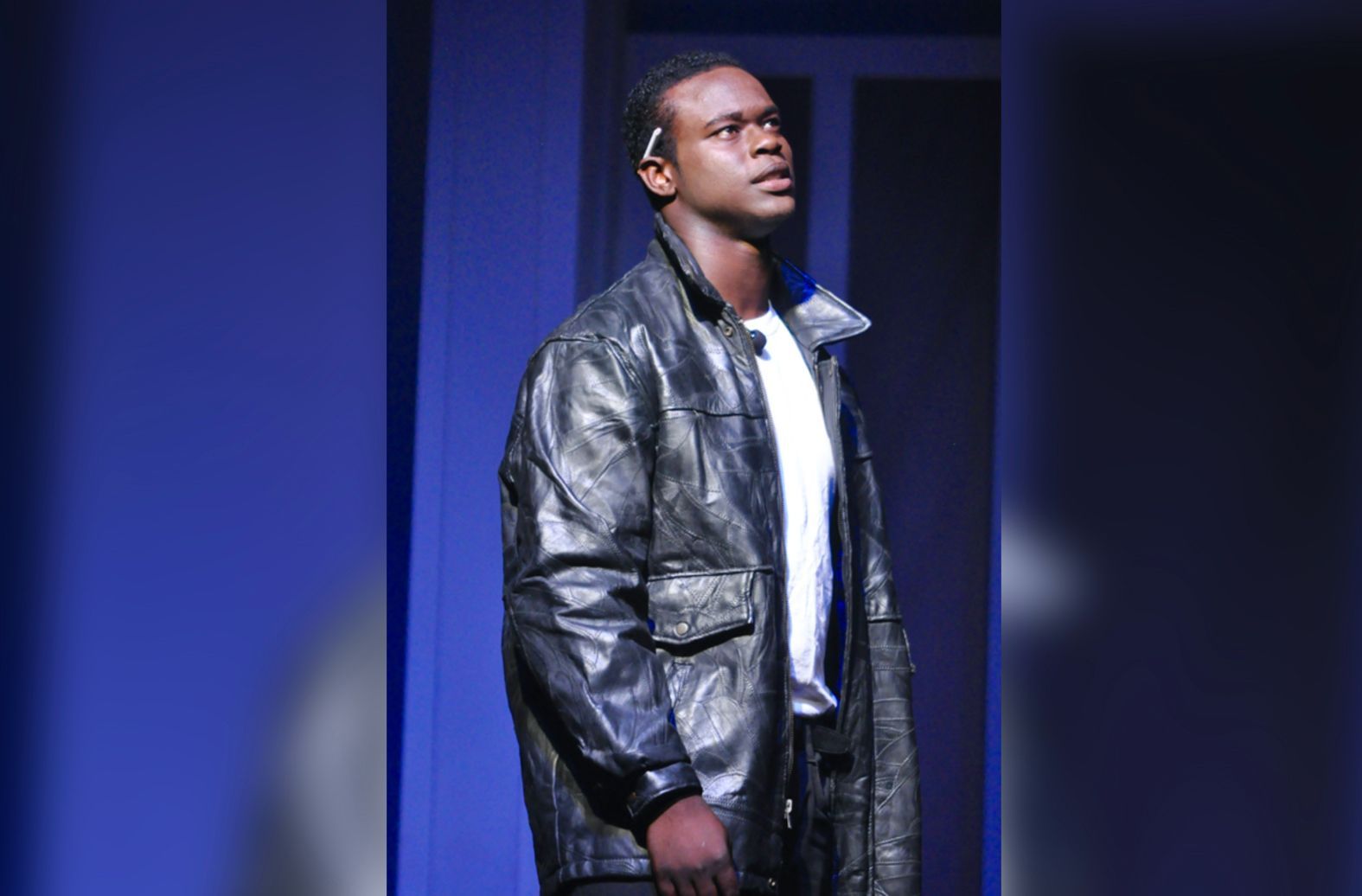 A man in a black leather jacket is standing on a stage