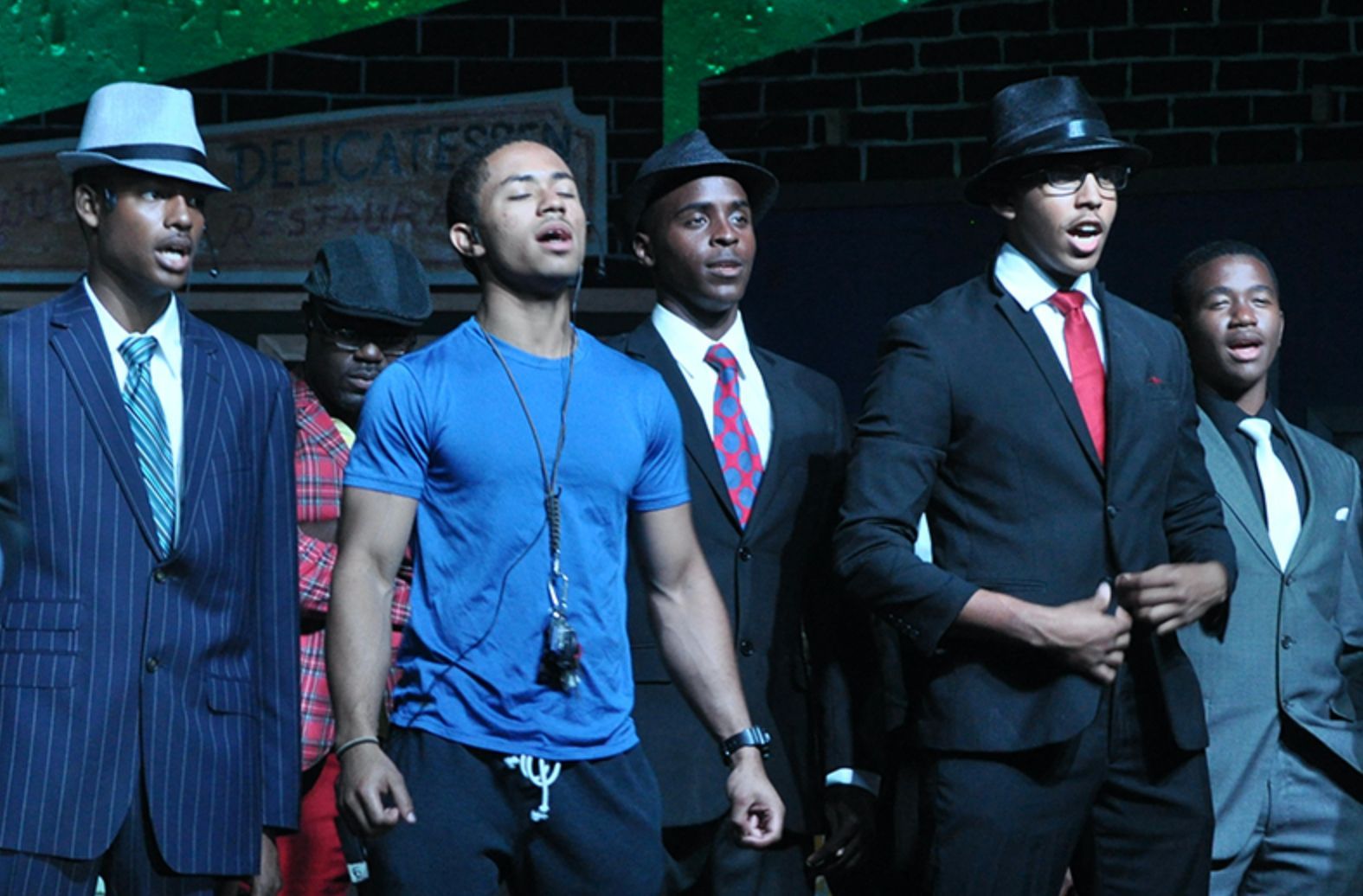 A group of men singing in front of a sign that says delicatessen