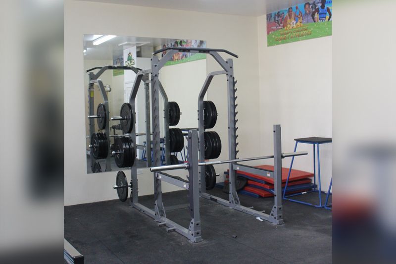 A gym with squat racks and a large mirror