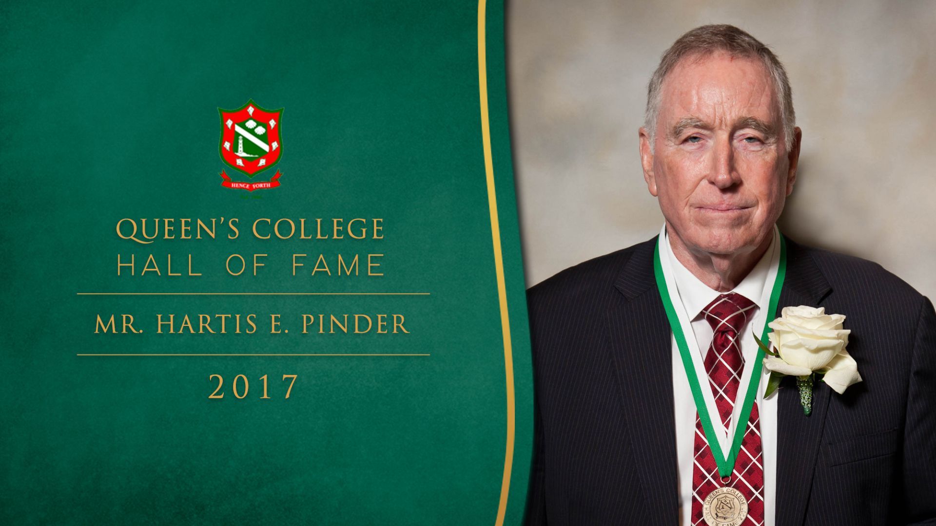 A man in a suit and tie is standing in front of a sign that says queens college hall of fame