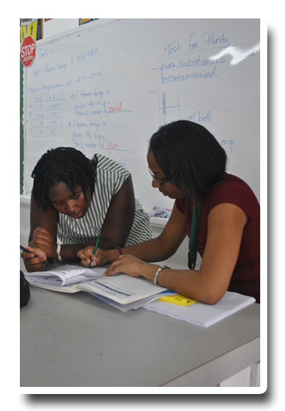 Two women sit at a desk in front of a stop sign