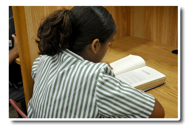 A girl in a green and white striped shirt is reading a book