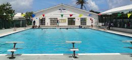A large swimming pool with a white building in the background.