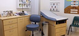 A doctor 's office with a blue chair and a blue table.