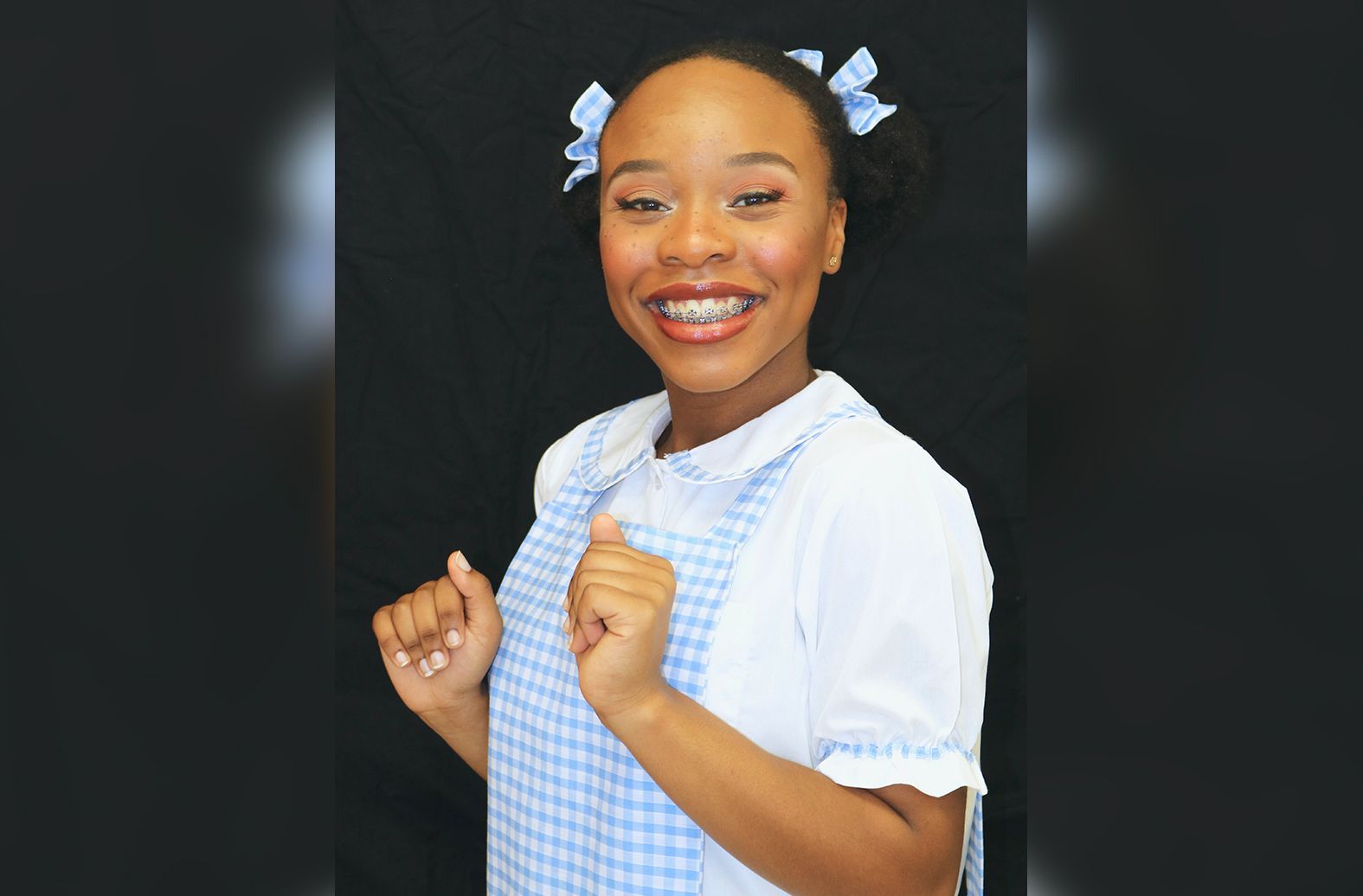 A woman in a blue and white checkered apron is smiling