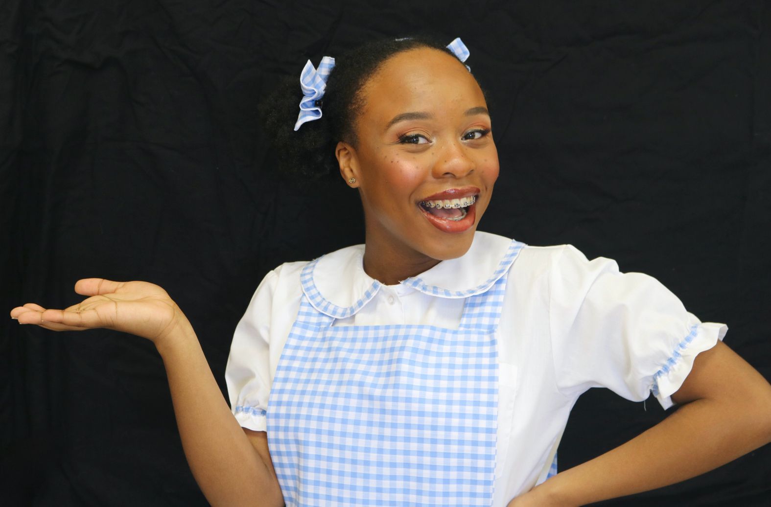 A girl in a blue and white checkered apron is smiling