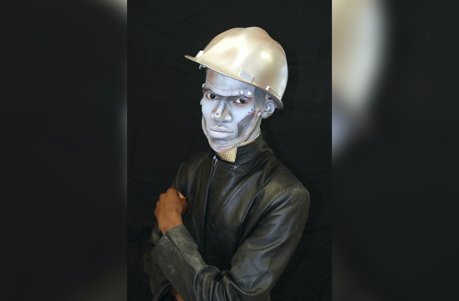 A man with silver paint on his face wearing a hard hat