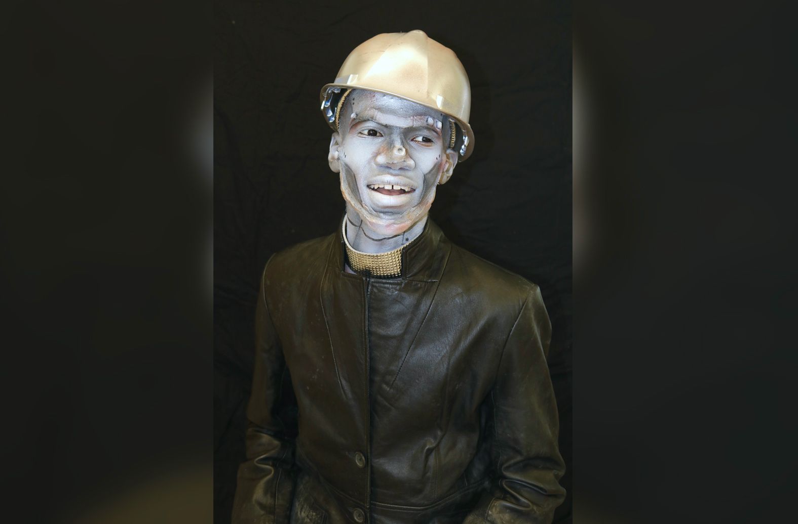 A man in a suit and hard hat is covered in silver paint