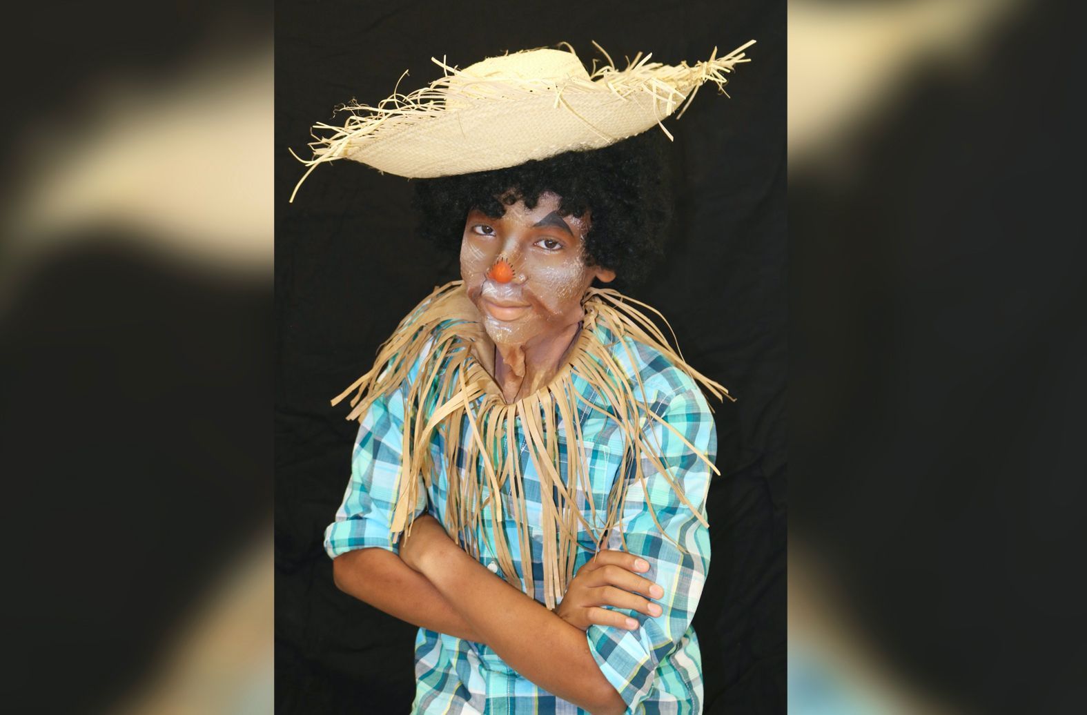 A boy dressed as a scarecrow with his arms crossed