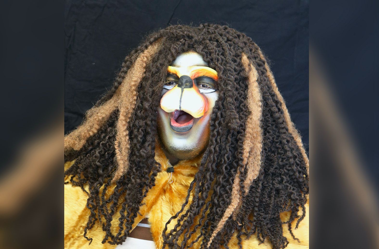 A person with dreadlocks and a face painted like a lion