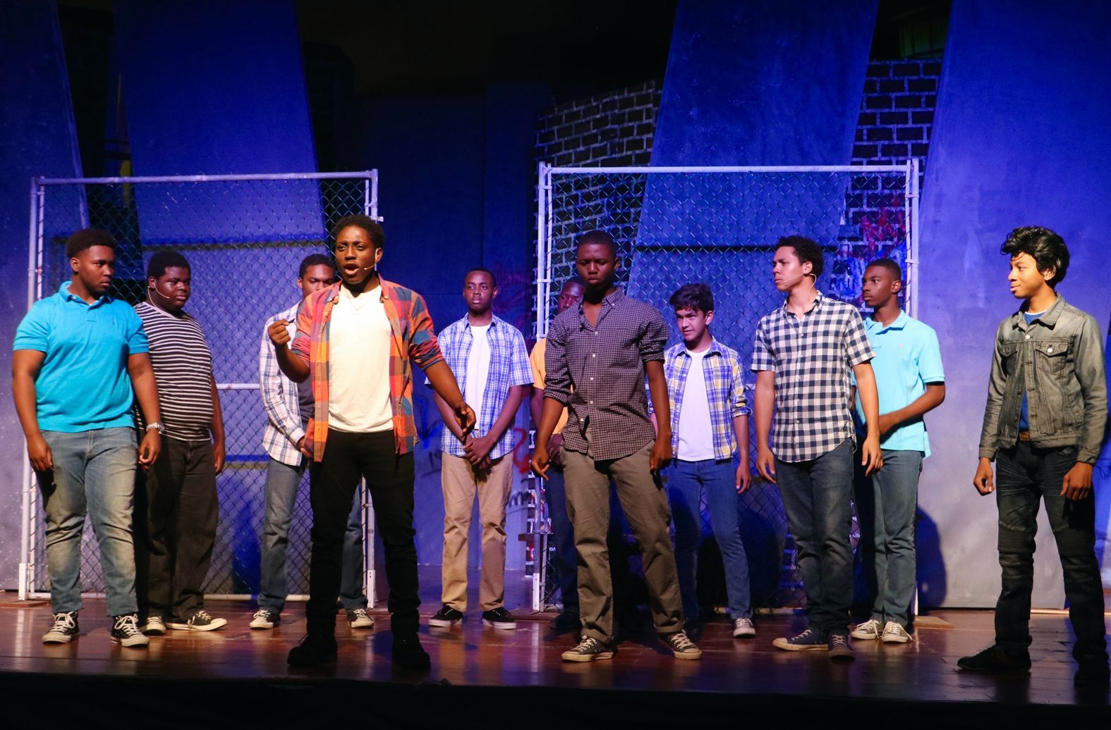 A group of young men standing on a stage in front of a fence