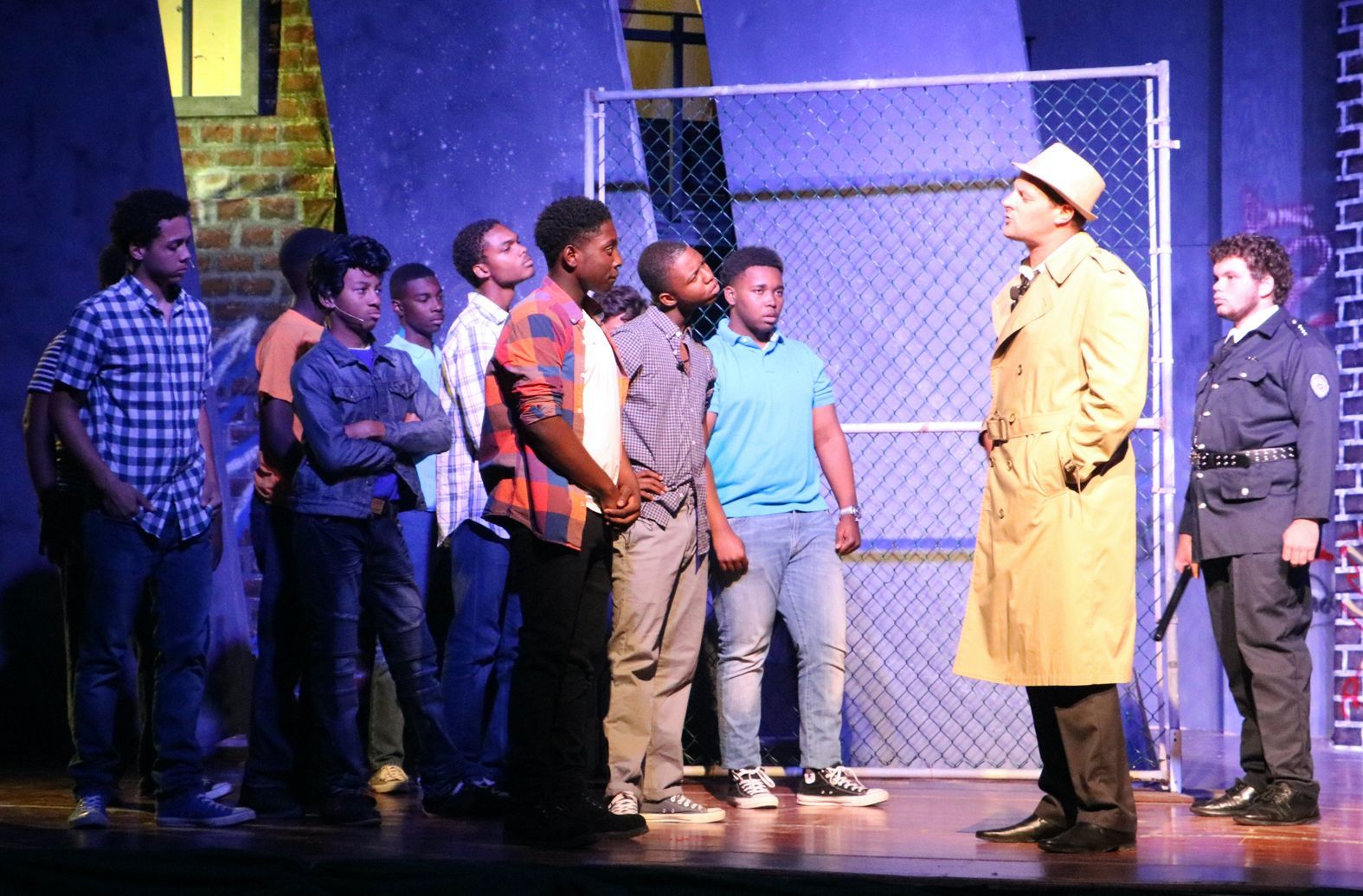 A man in a trench coat talks to a group of young men