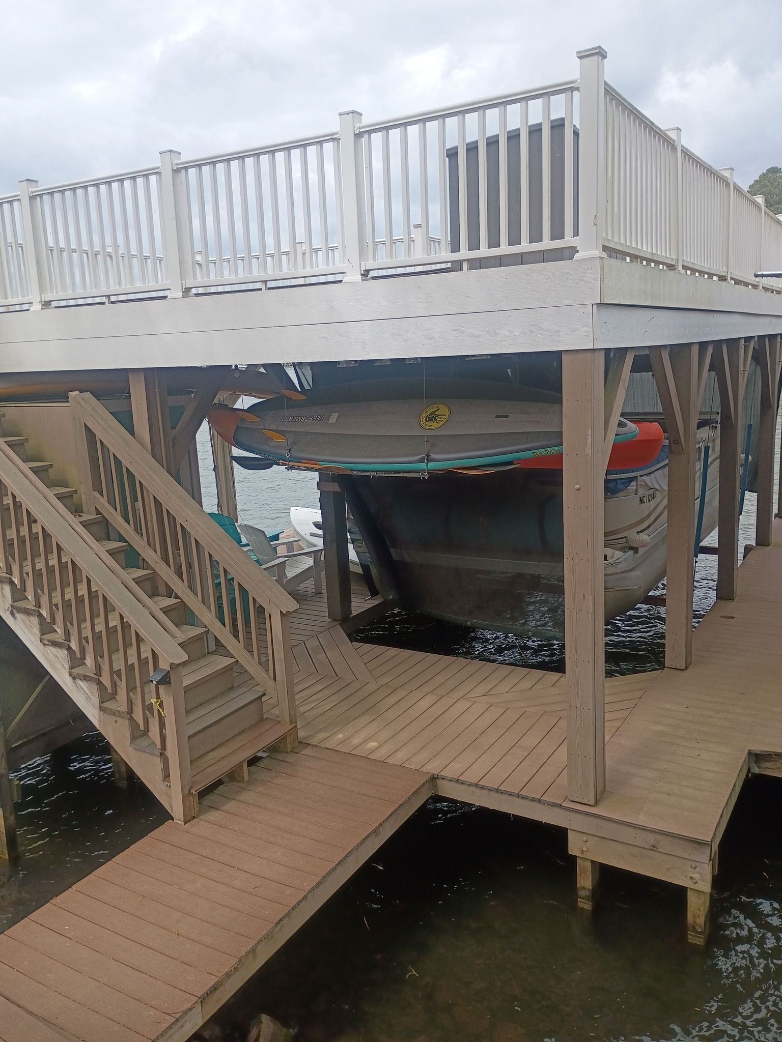 Boat on a dock beneath a white-railed deck and stairs over water