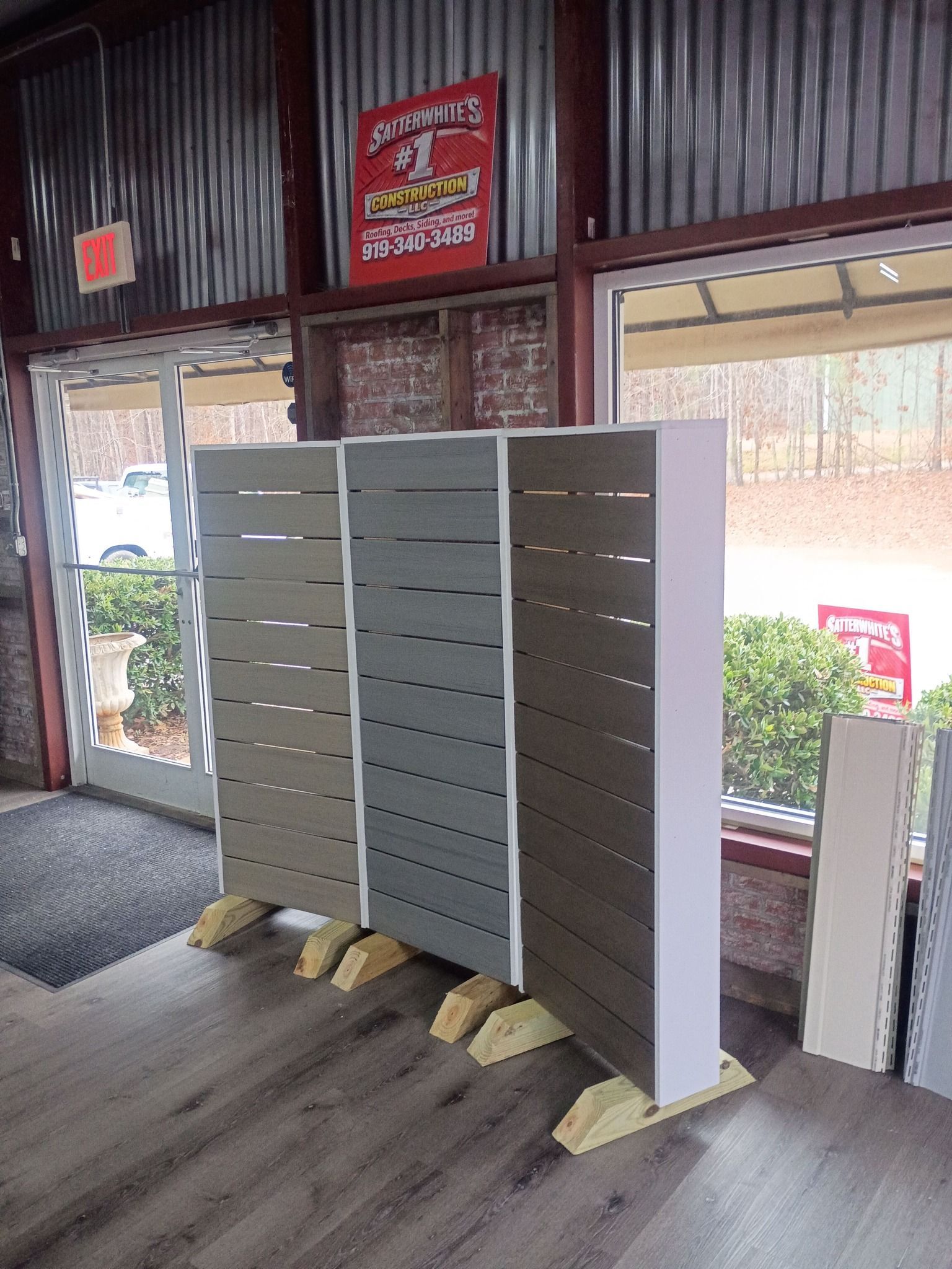 Three tall gray mailboxes on a wooden floor near a bright entrance doorway