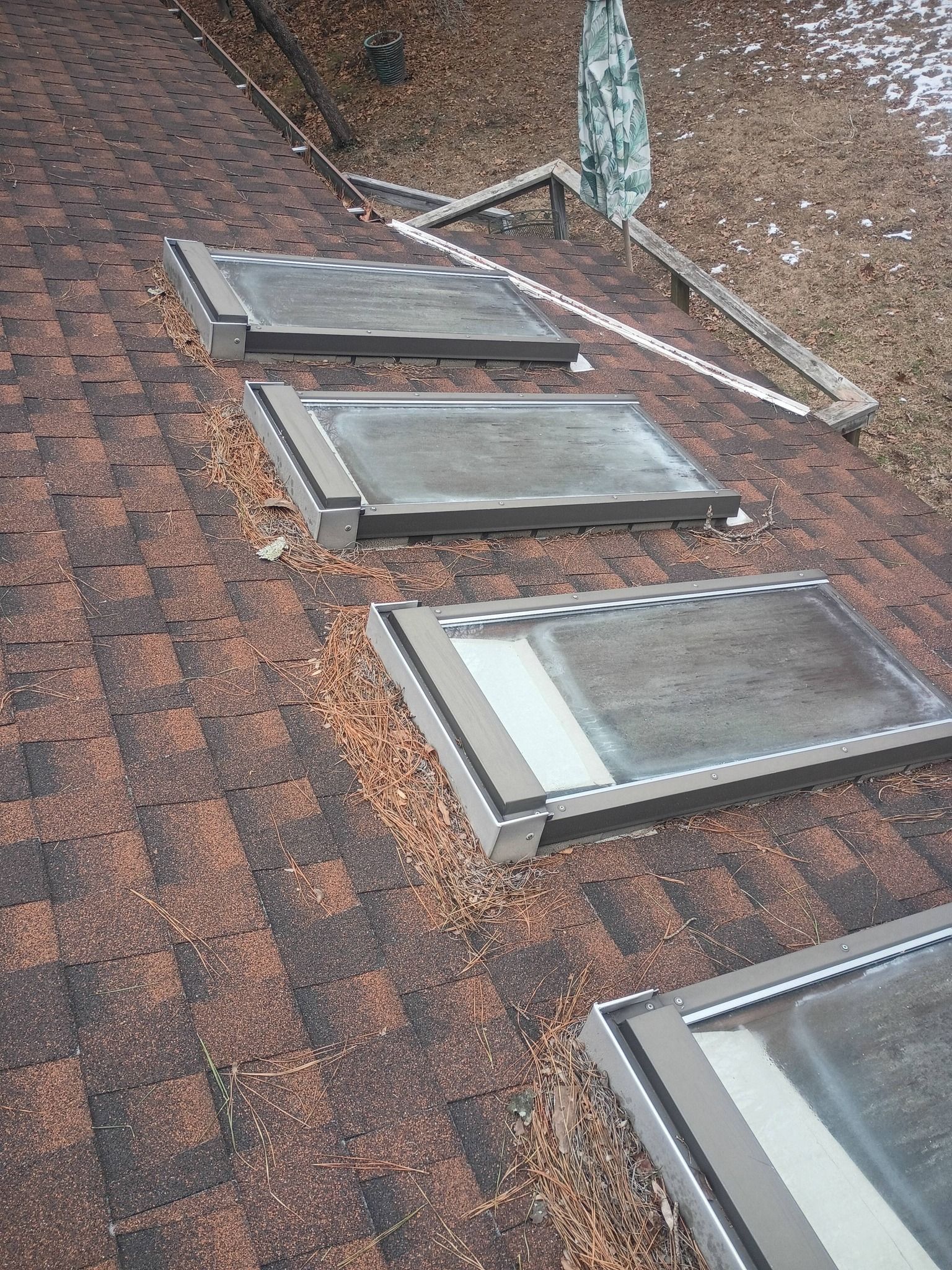 Roof with four skylights and a vent pipe on weathered shingles
