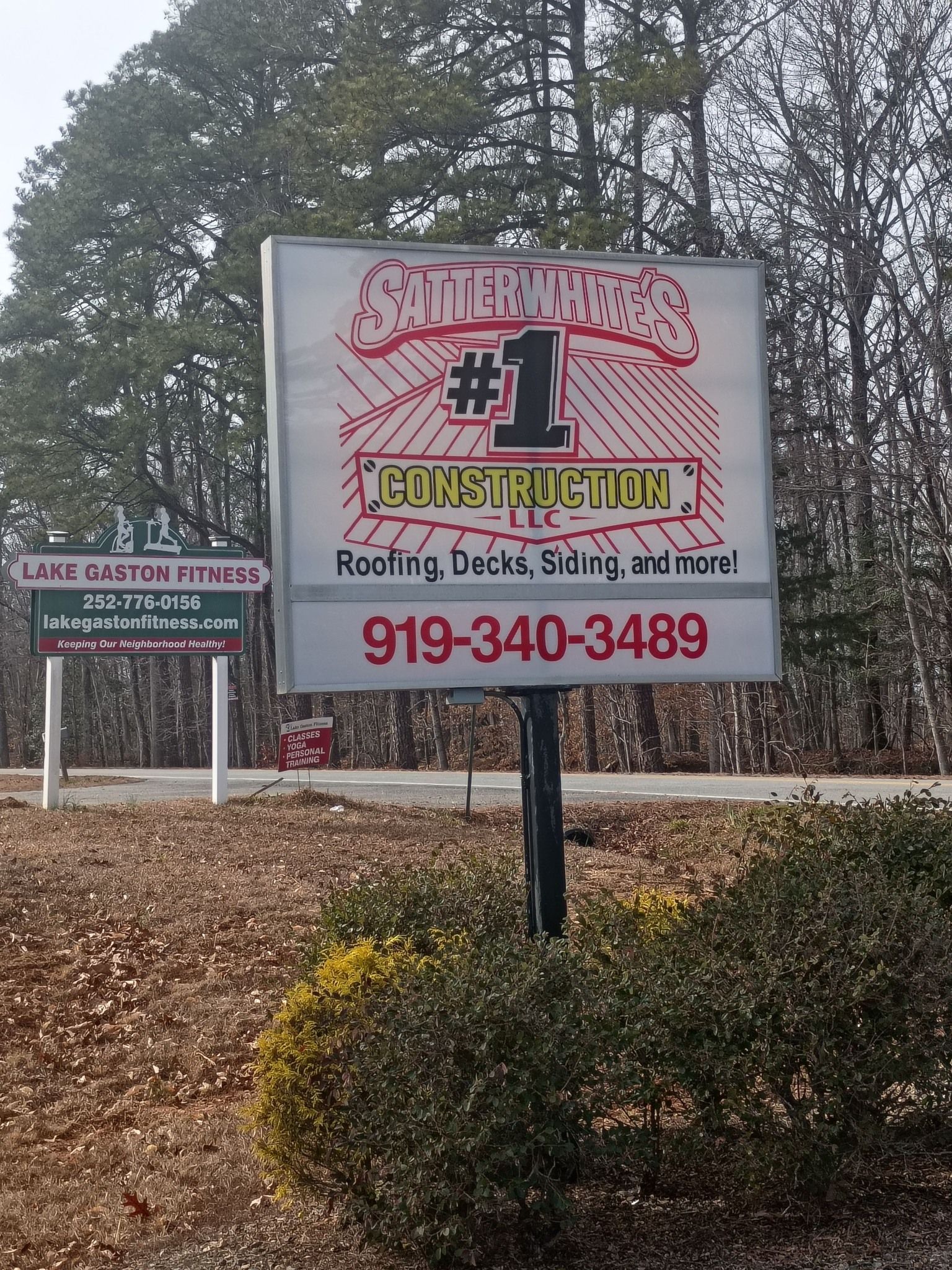 Outdoor sign for “Smith’s #1” roofing and siding with phone number 919-340-3489, beside a small sign and shrubs