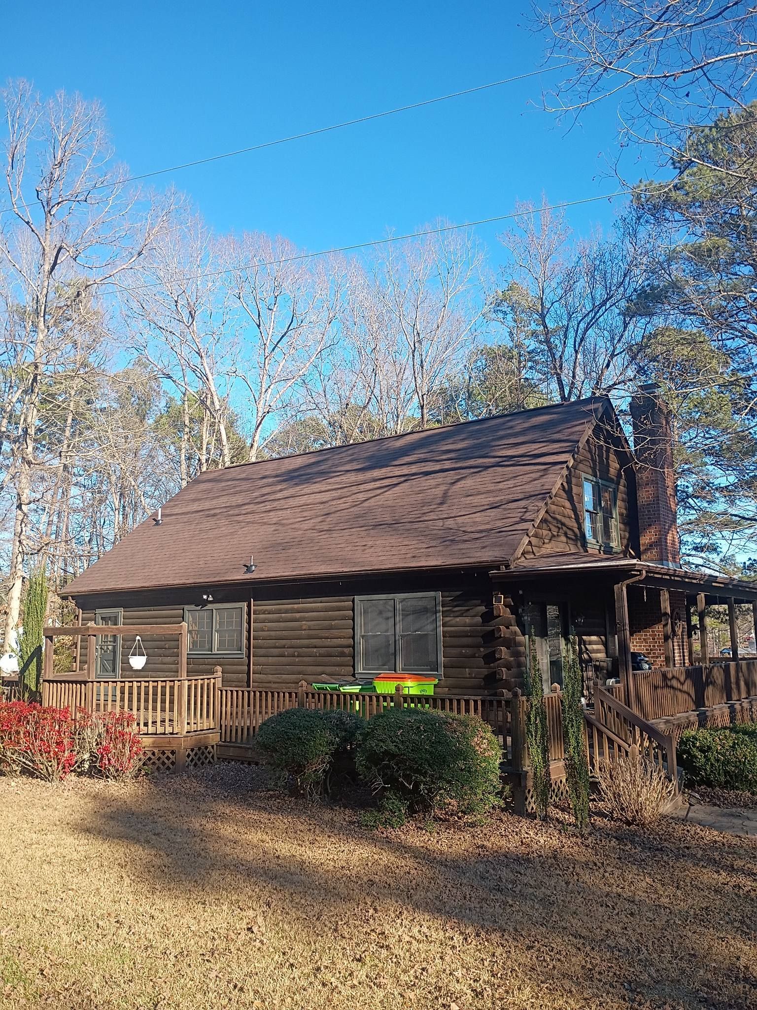 Rustic wooden cabin with a steep roof amid autumn trees under a clear blue sky