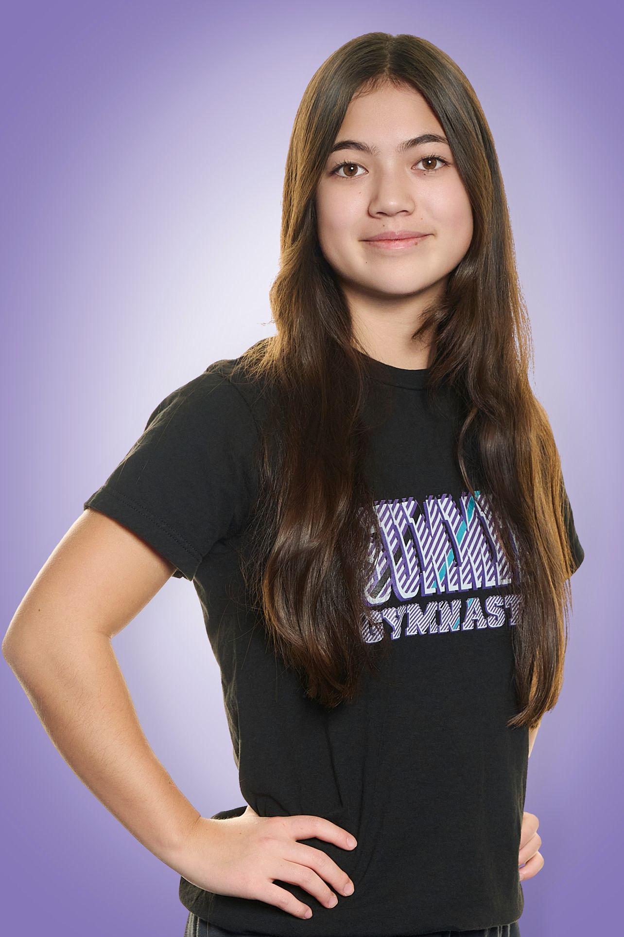 Young woman in a black T-shirt posing with hands on hips against a purple background
