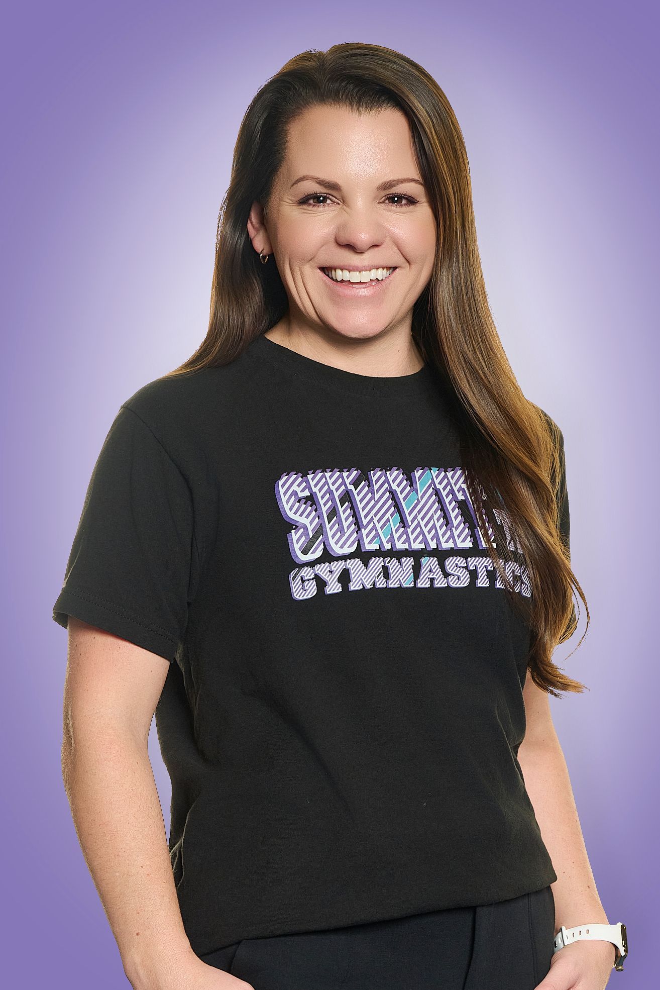 Woman in a black “Gymnast” T-shirt smiling against a purple background