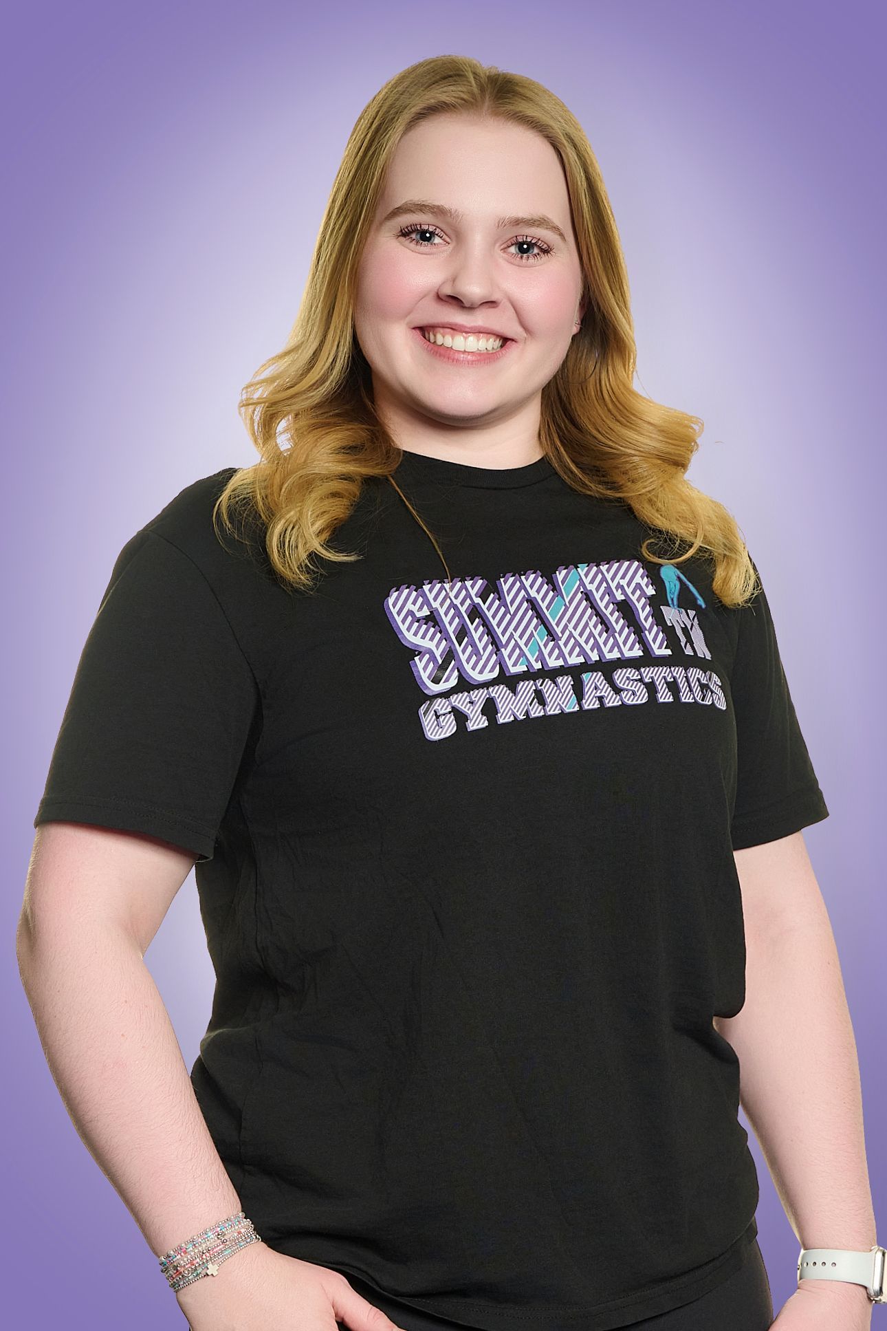 Smiling person in a black T-shirt standing against a purple backdrop