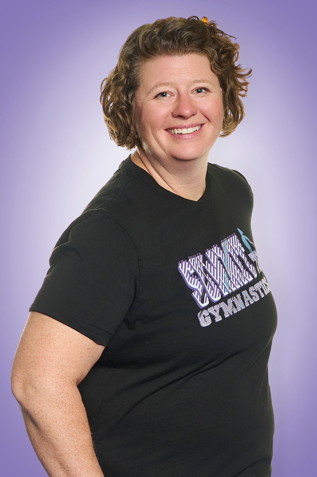 Smiling person in a black T-shirt with white text against a purple background
