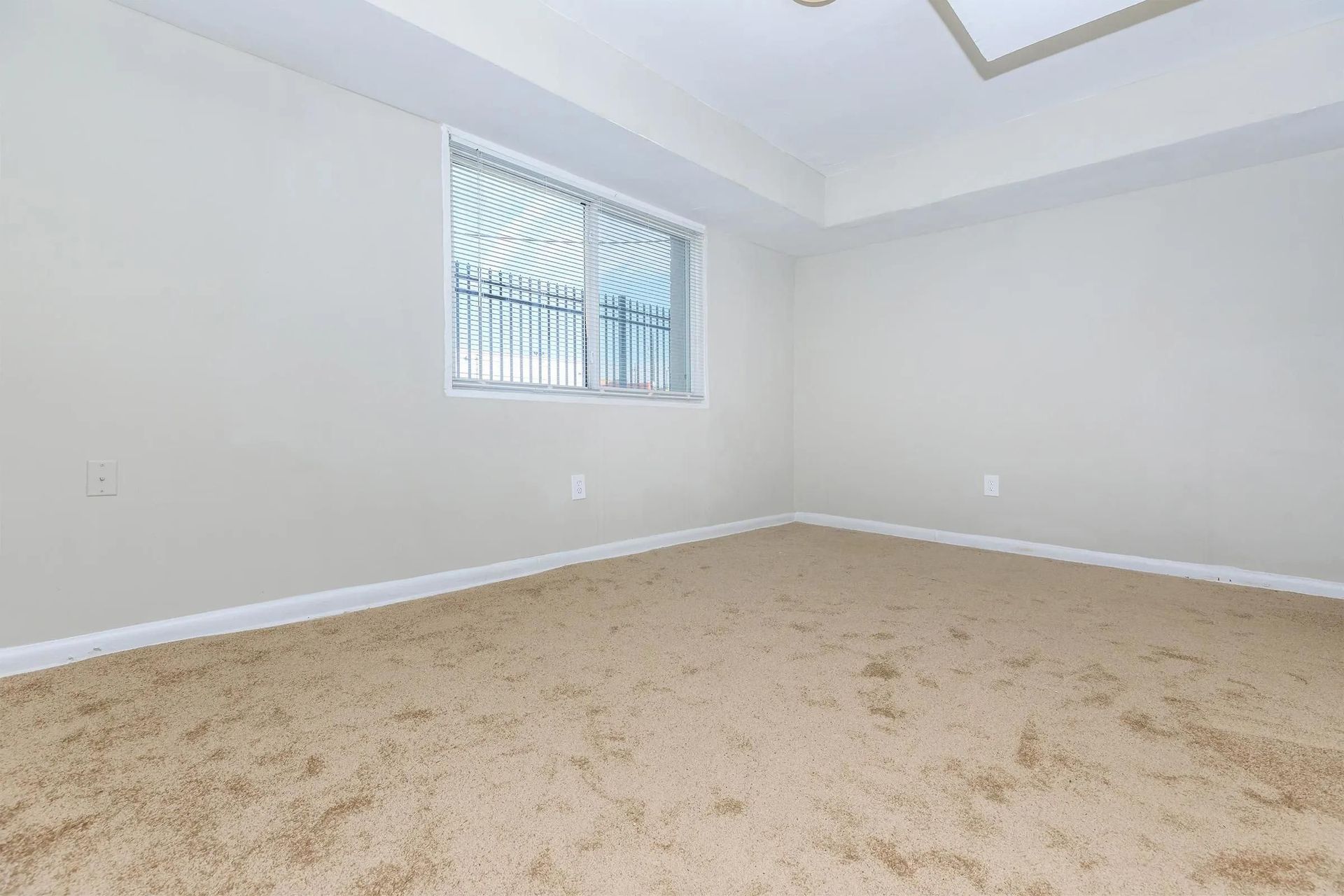 An empty bedroom with a window and a ceiling fan.