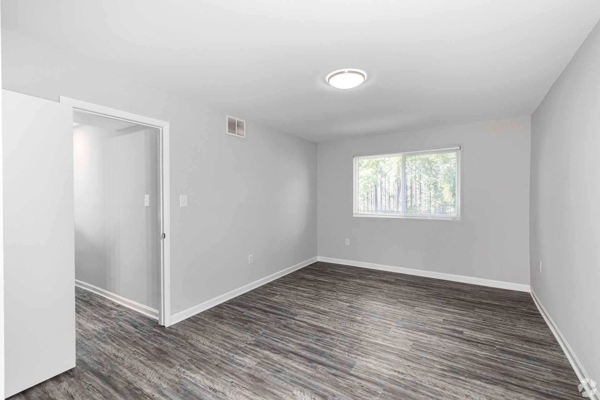 An empty room with a wooden floor and a window.