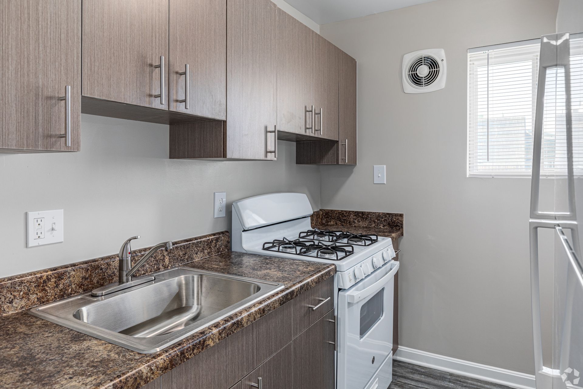 A kitchen with a stove , sink , refrigerator and window.