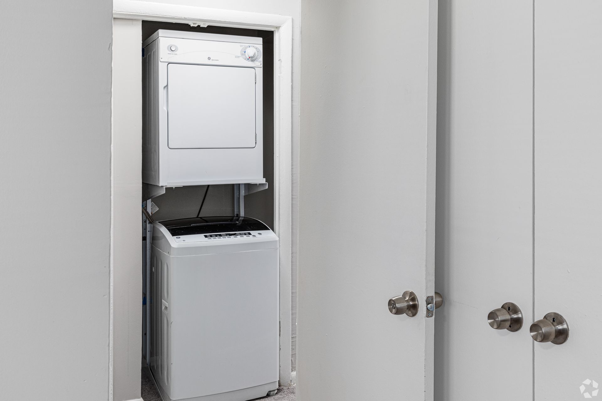 A washer and dryer are stacked on top of each other in a closet.