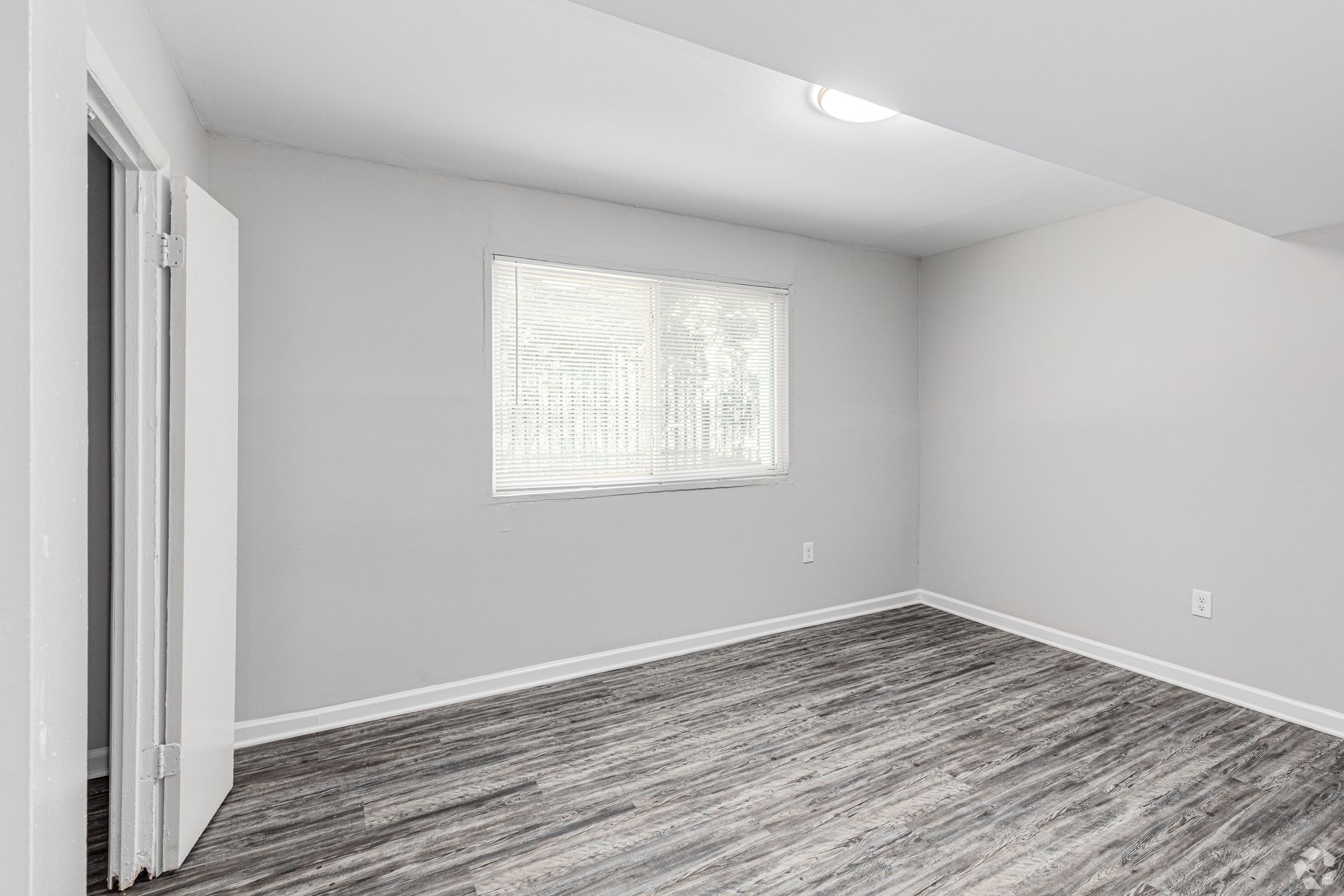 An empty bedroom with hardwood floors and a window.